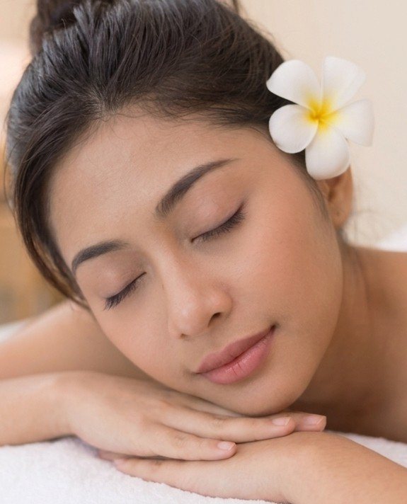 A woman relaxing with eyes closed and a white flower in her hair